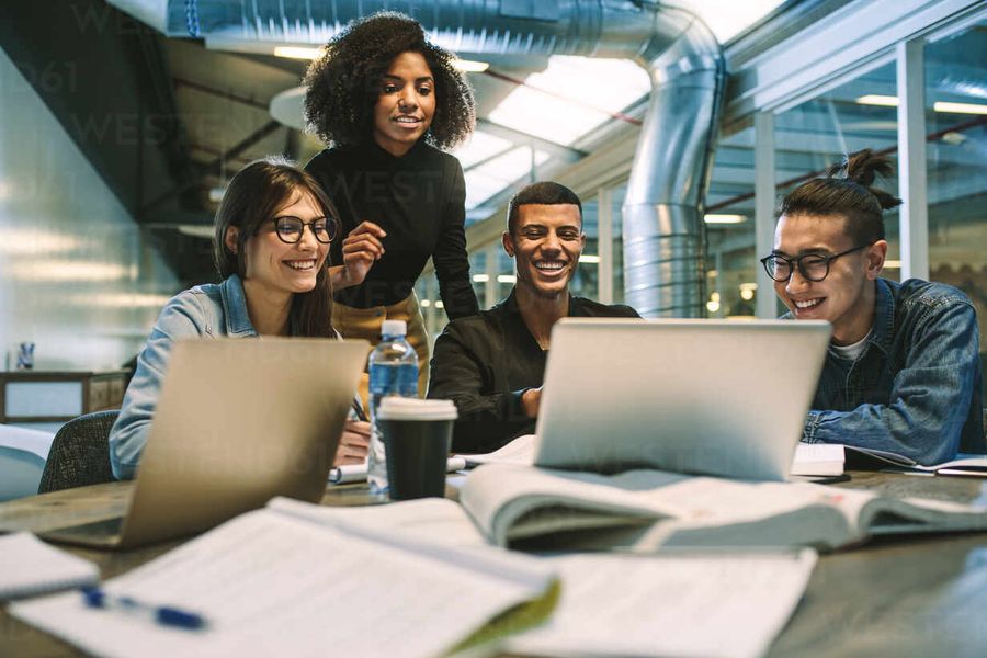 Equipo de trabajo sonriendo frente a sus laptops