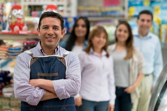 Dueño de un comercio sonriendo junto a su equipo de trabajo