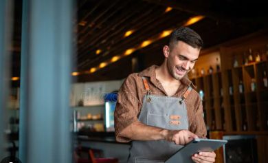 Encargado de restaurante sonriendo mientras usa una tableta